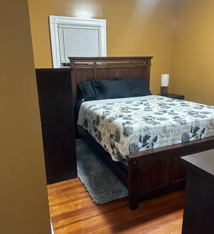 A bed room with a neatly made bed and a window