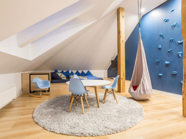 A room with a table and chairs, a swing set and a rock wall.