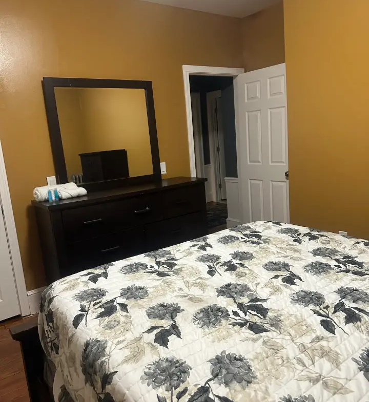 A bedroom with a bed, dresser and mirror.