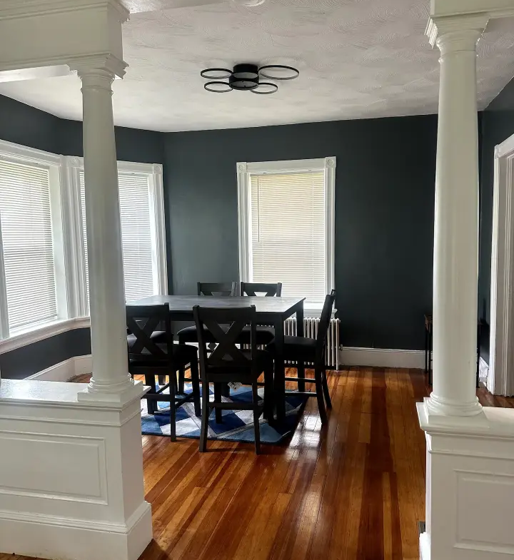 A dining room with dark walls and wood floors.