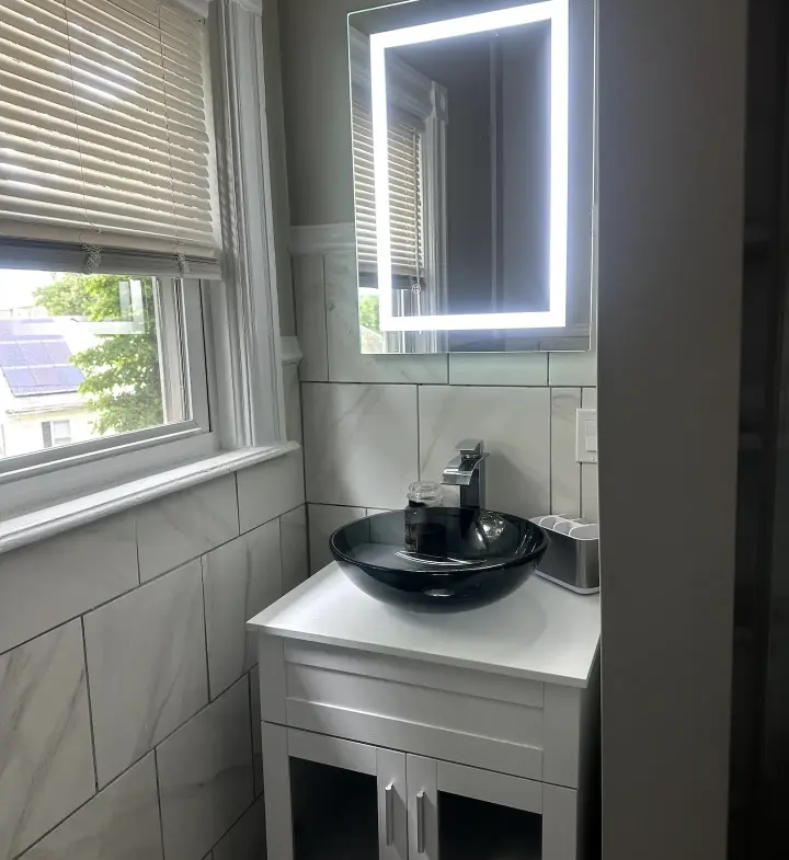 A bathroom with a sink, mirror and window.