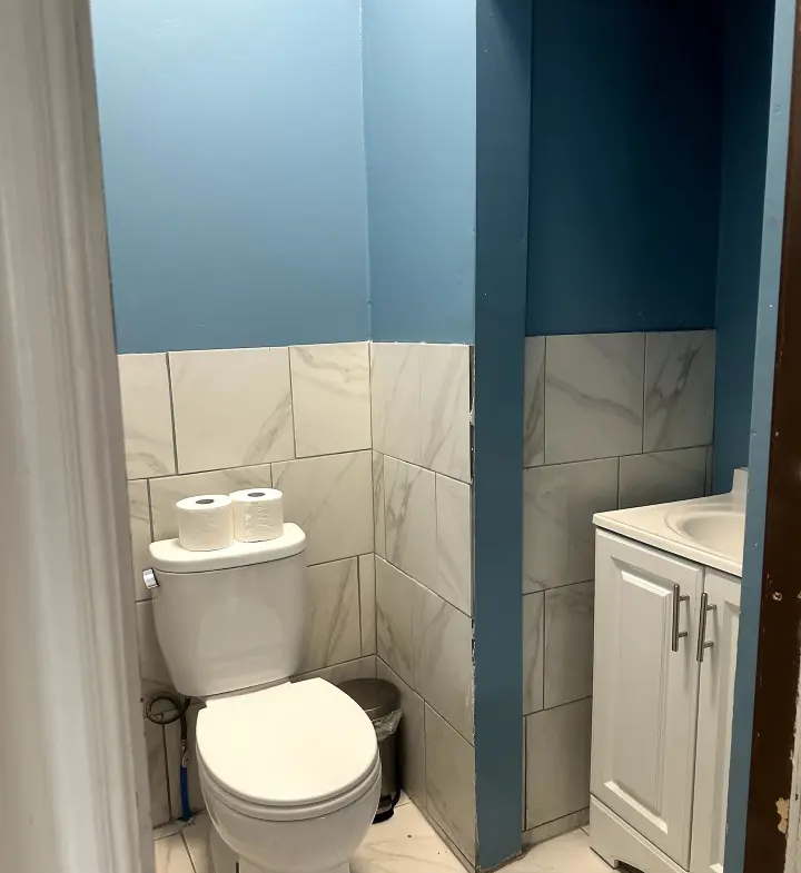 A bathroom with blue walls and white tile.