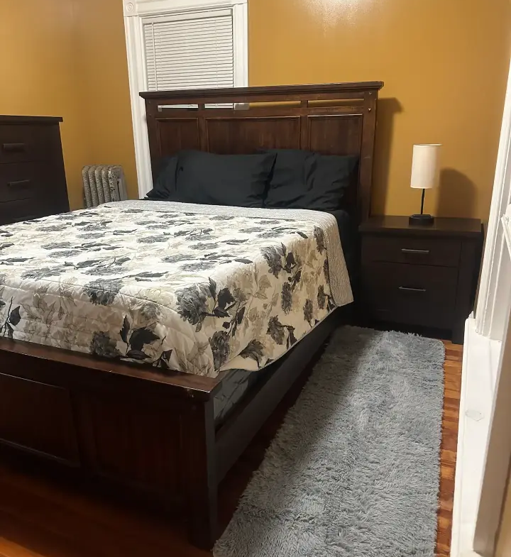 A bedroom with a bed, nightstand and dresser.