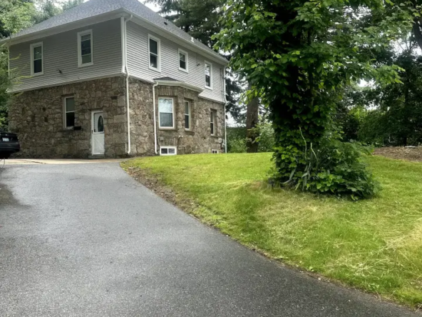 A house with a driveway and trees in the background