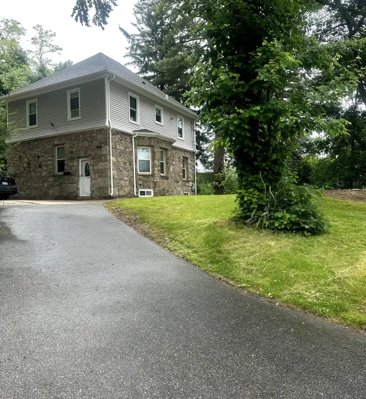 A house with a driveway and trees in the background