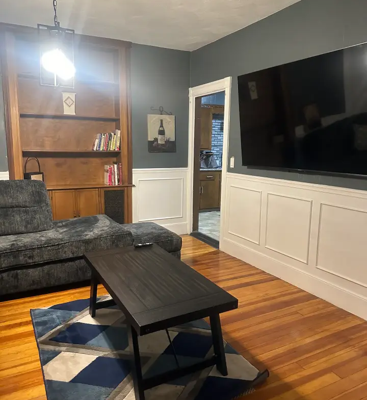 A living room with a couch, chair and television.