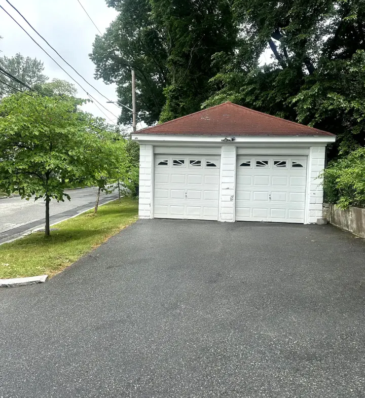 A two car garage with trees in the background.