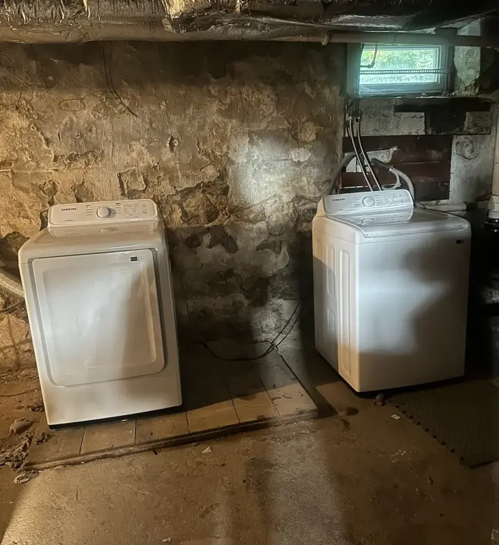 Two white appliances in a room with stone walls.