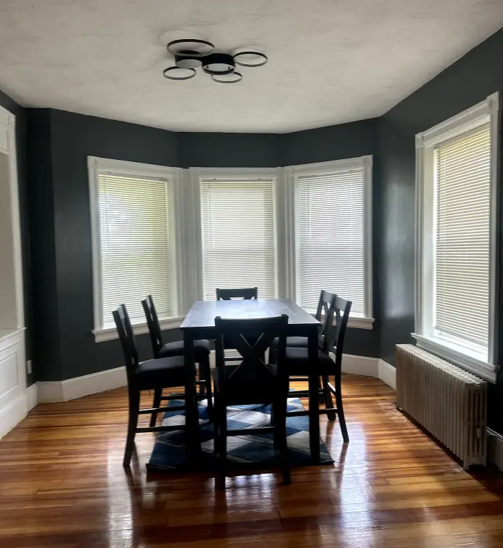 A dining room with dark walls and wooden floors.