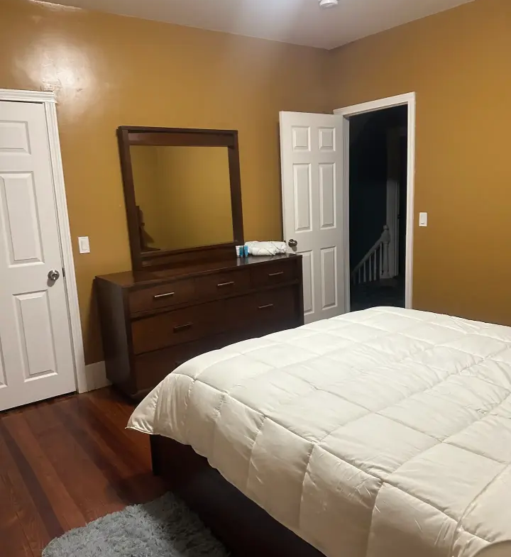 A bedroom with a bed, dresser and mirror.