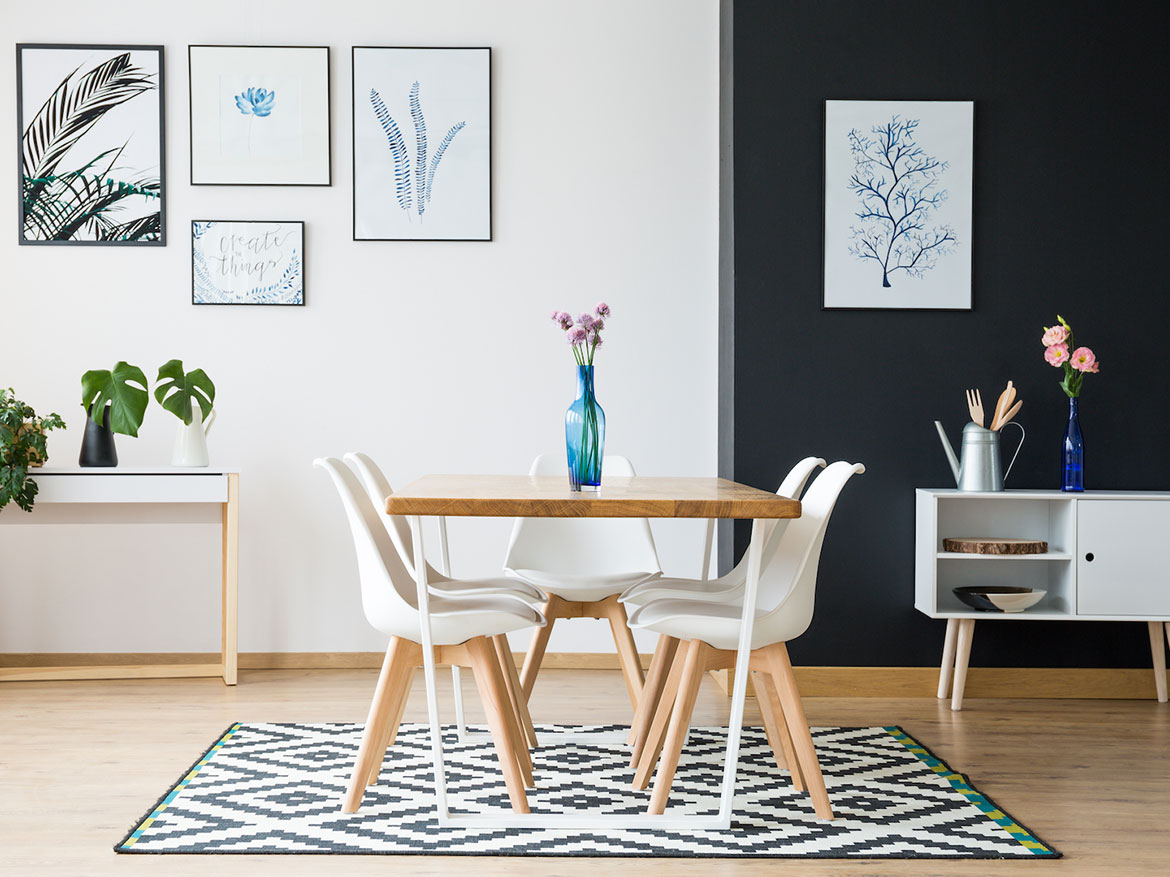 A dining room table with four chairs and a vase of flowers.