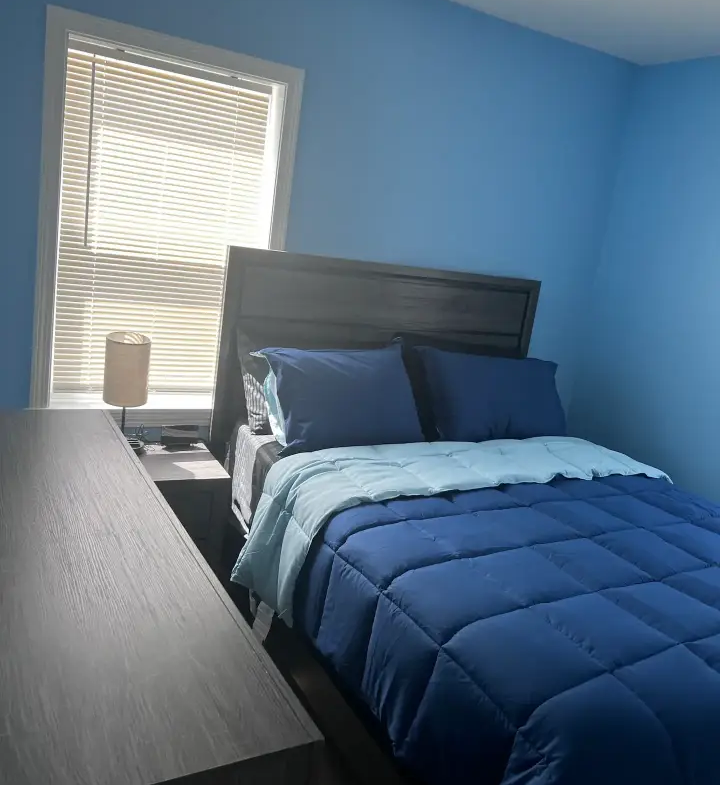 A bedroom with blue walls and a bed.