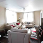 A living room with white furniture and red accents.