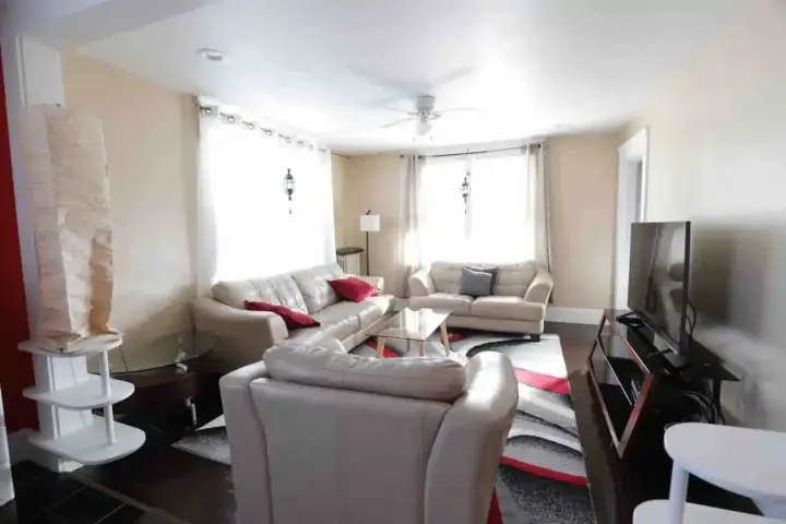 A living room with white furniture and red accents.