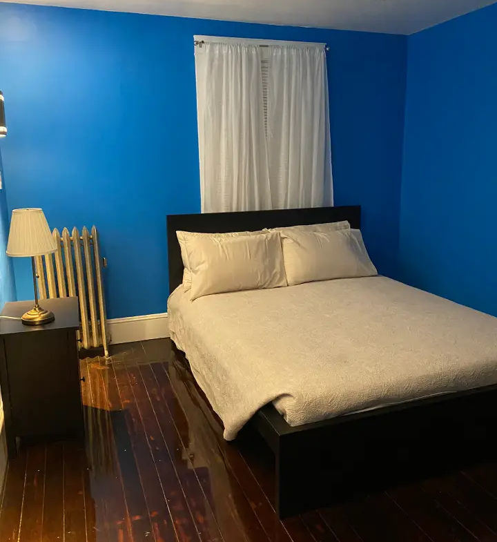 A bedroom with blue walls and wooden floors.