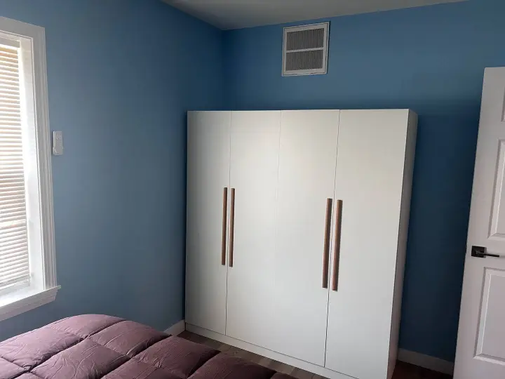 A bedroom with blue walls and white furniture.