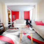 A living room with red walls and white furniture.