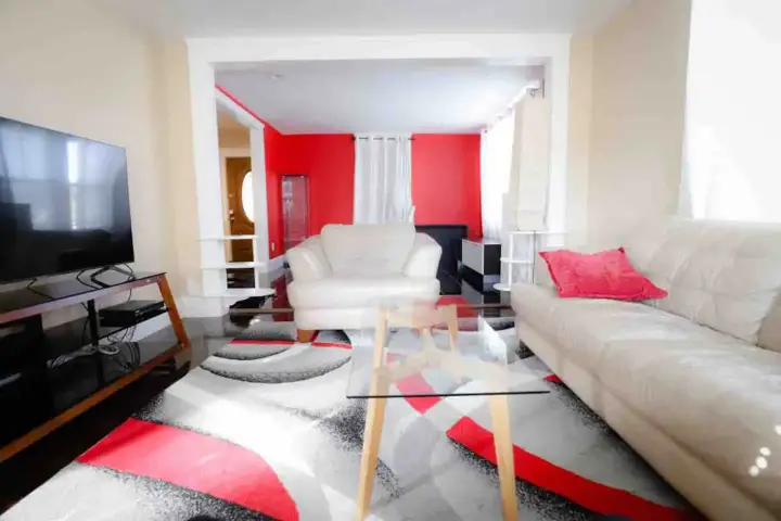 A living room with red walls and white furniture.