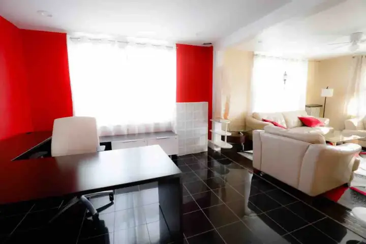 A living room with red walls and black tile flooring.