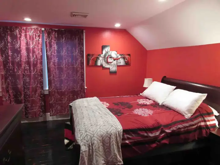 A bedroom with red walls and a black bed.