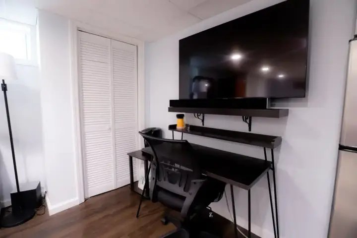 A desk with a chair and television on the wall.