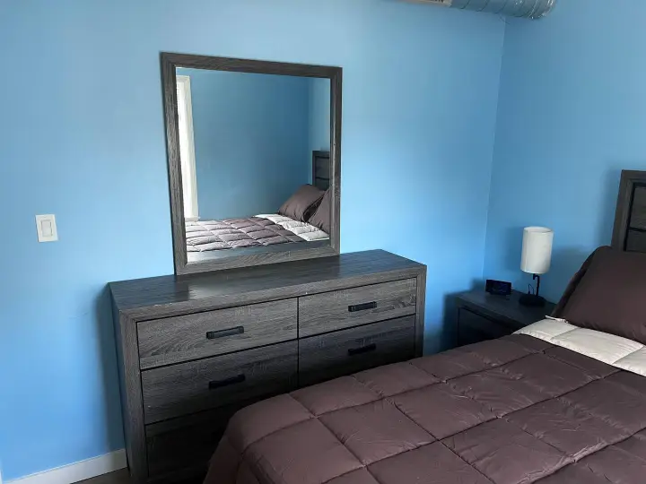 A bedroom with blue walls and brown furniture.