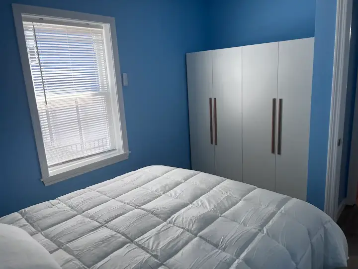 A bedroom with blue walls and white furniture.