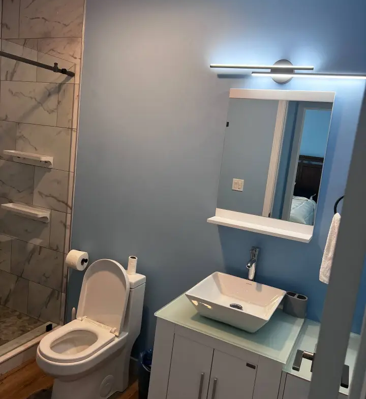 A bathroom with blue walls and white fixtures.