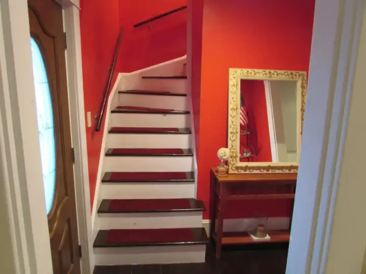 A red wall with stairs and mirror in the center.