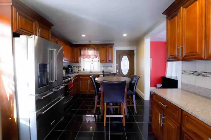 A kitchen with black tile floor and wooden cabinets.