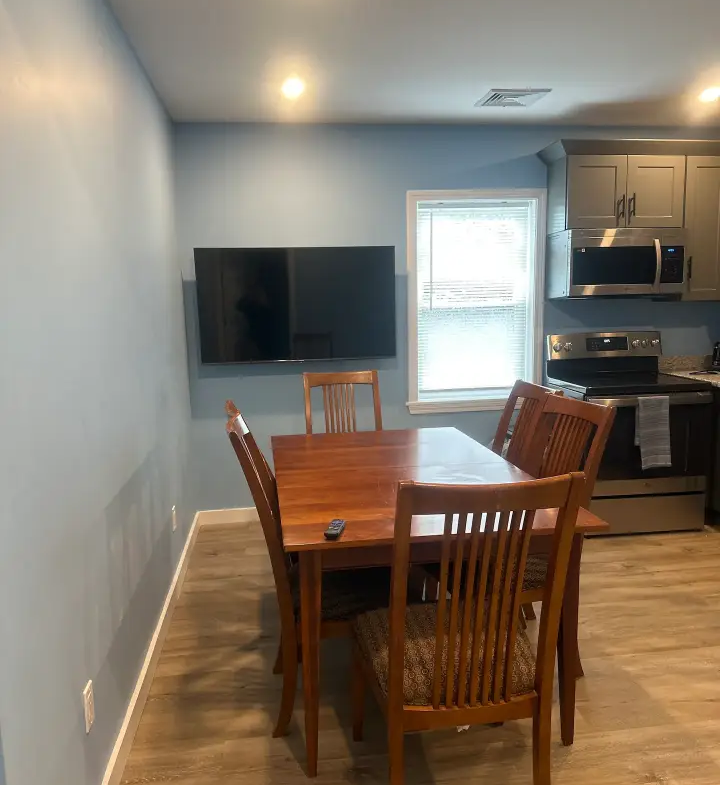 A dining room table and chairs in front of the kitchen.