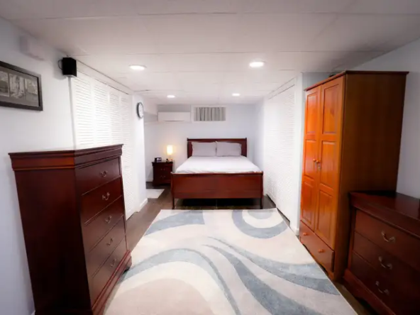 A bedroom with a bed, dresser and nightstand.