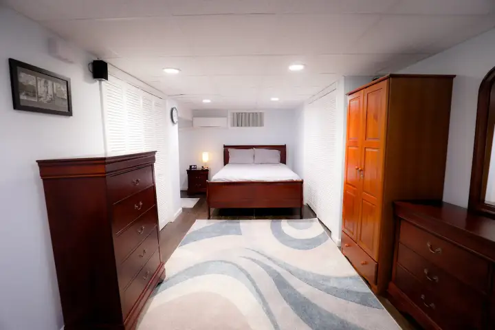 A bedroom with a bed, dresser and nightstand.