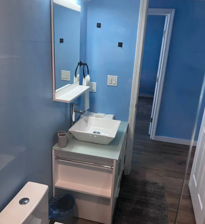 A bathroom with blue walls and wooden floors.