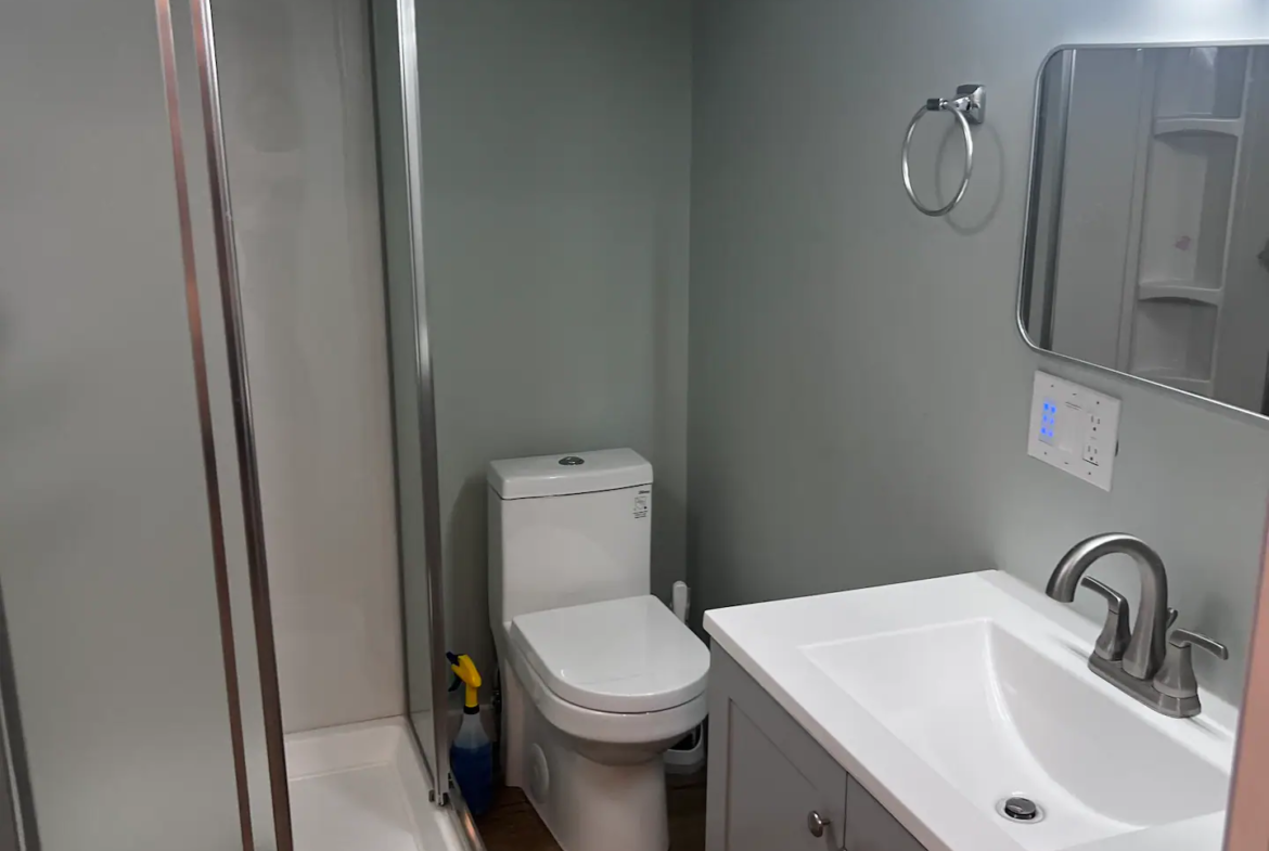 A bathroom with a toilet, sink and shower.