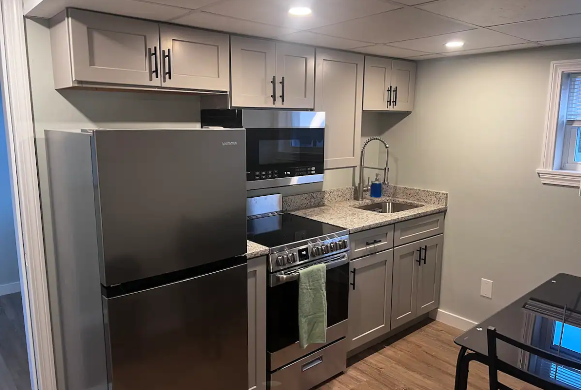 A kitchen with stainless steel appliances and grey cabinets.