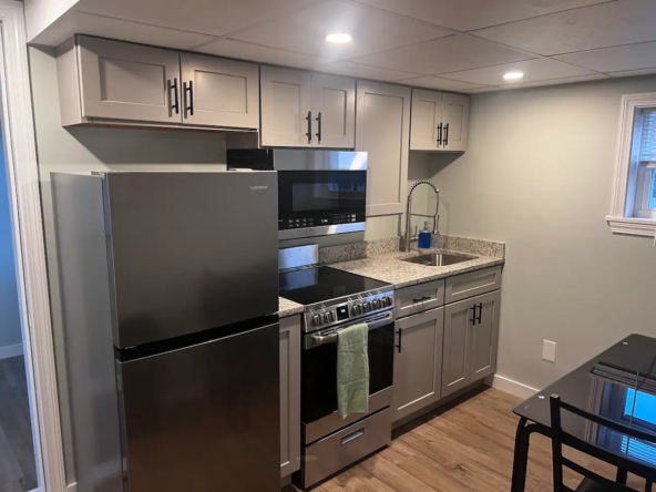 A kitchen with stainless steel appliances and grey cabinets.