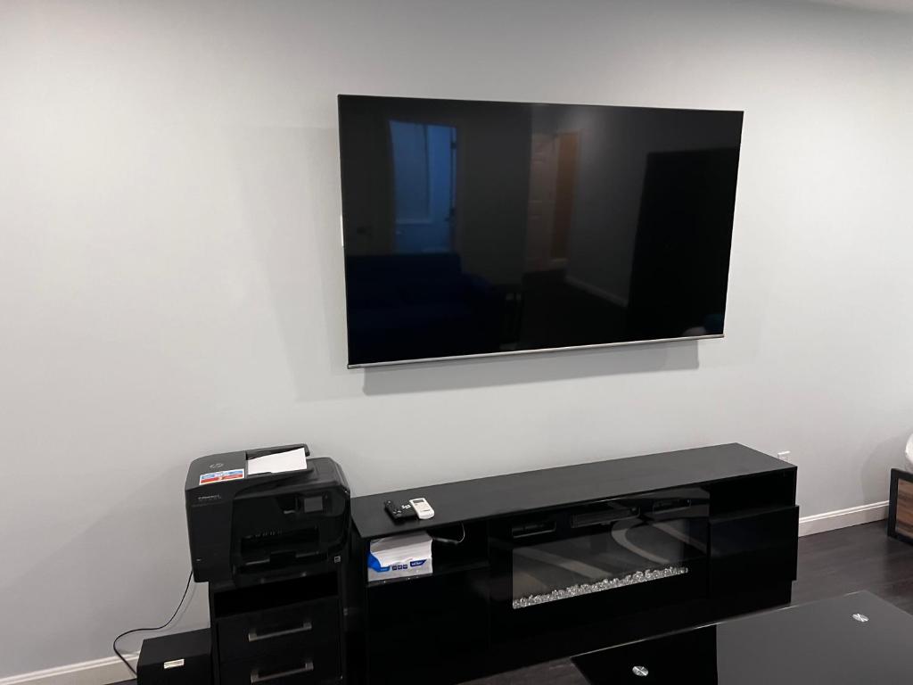 A tv mounted on the wall above a printer.