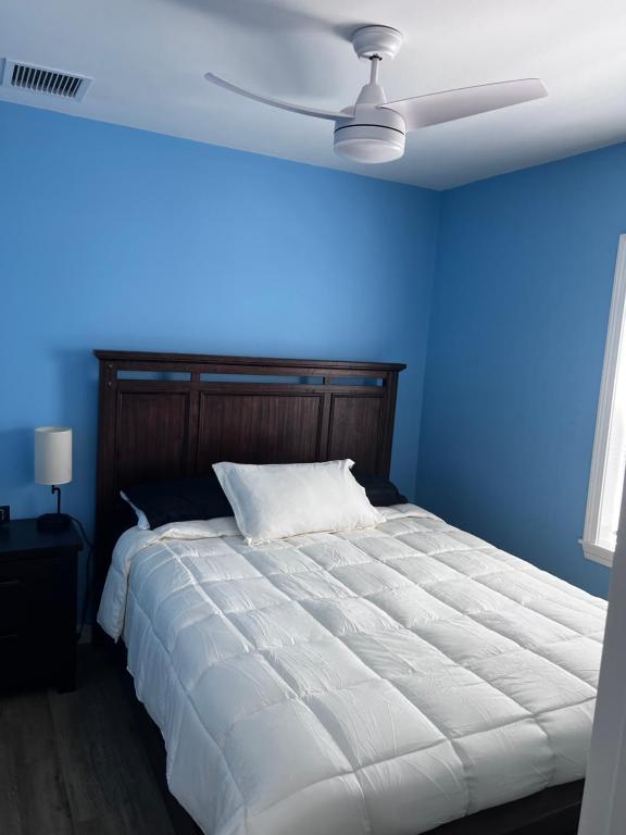 A bedroom with blue walls and white bedding.