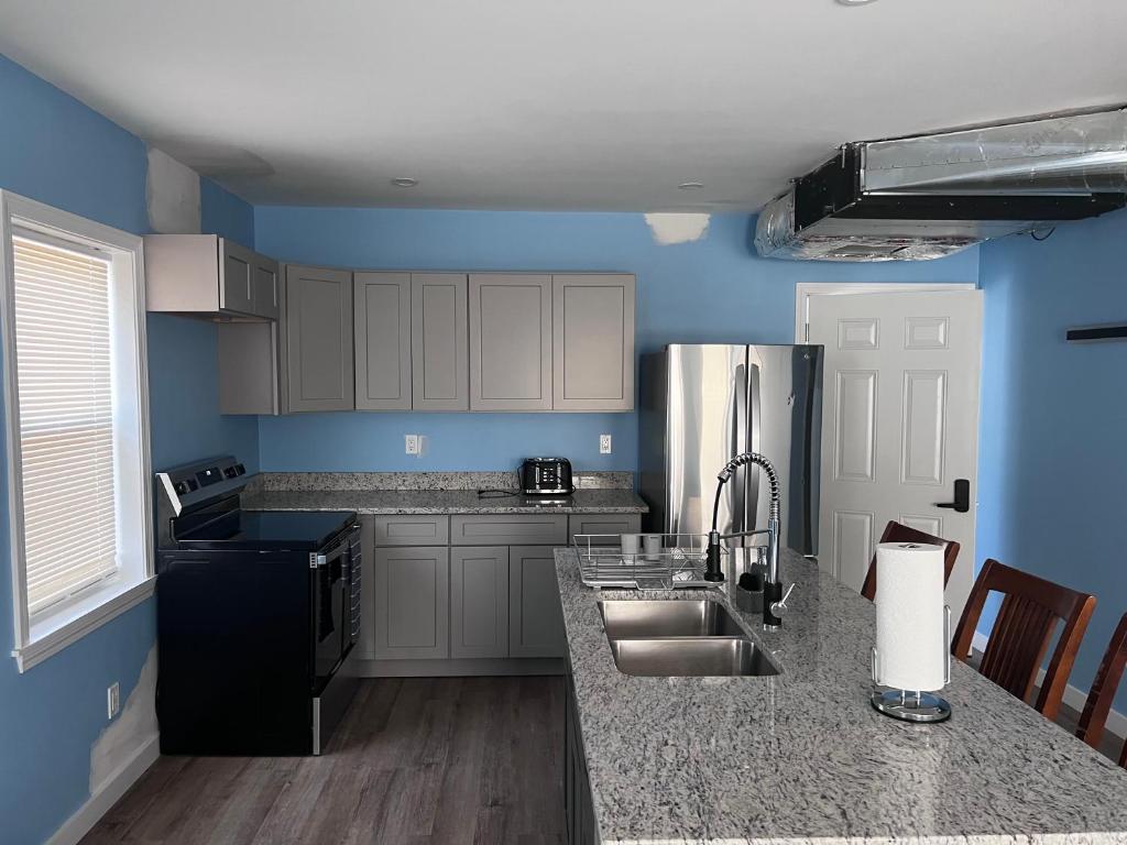 A kitchen with blue walls and grey cabinets.