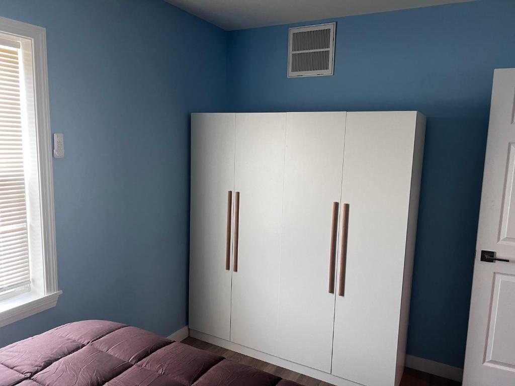 A bedroom with blue walls and white furniture.