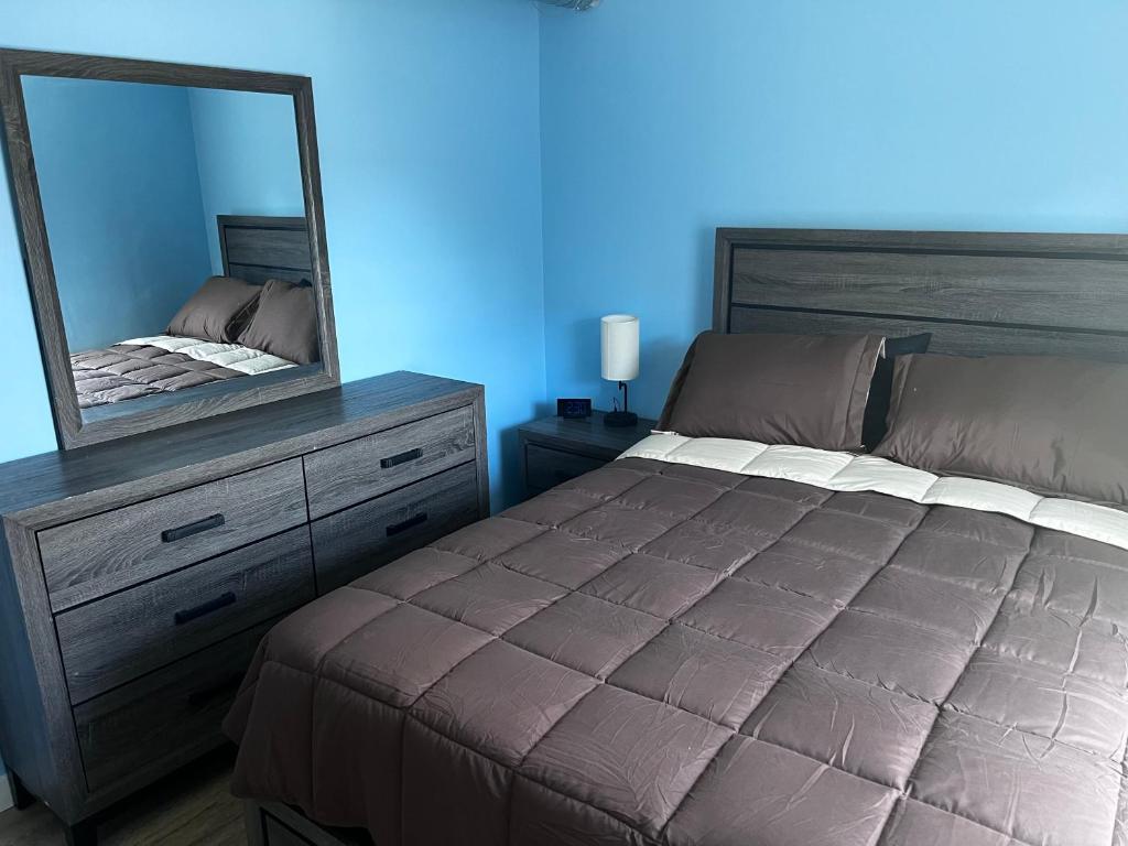 A bedroom with blue walls and brown furniture.