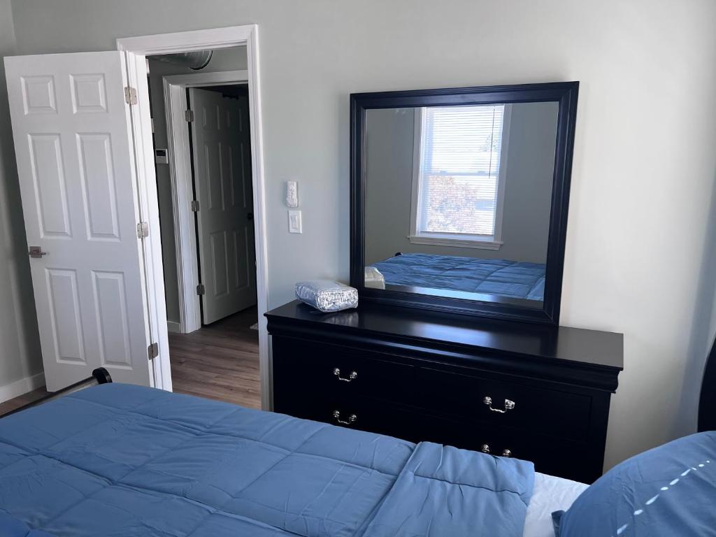 A bedroom with a bed, dresser and mirror.