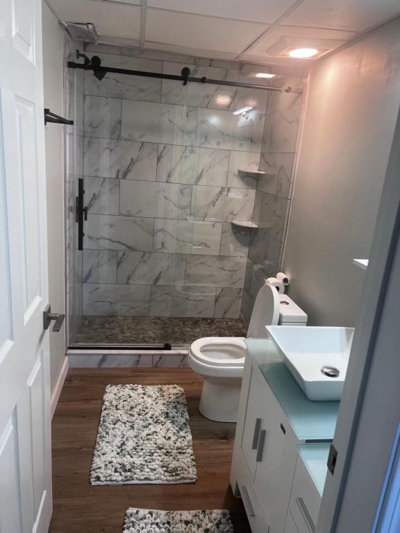 A bathroom with a toilet, sink and shower.