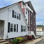 A white and red building with a porch on the side.